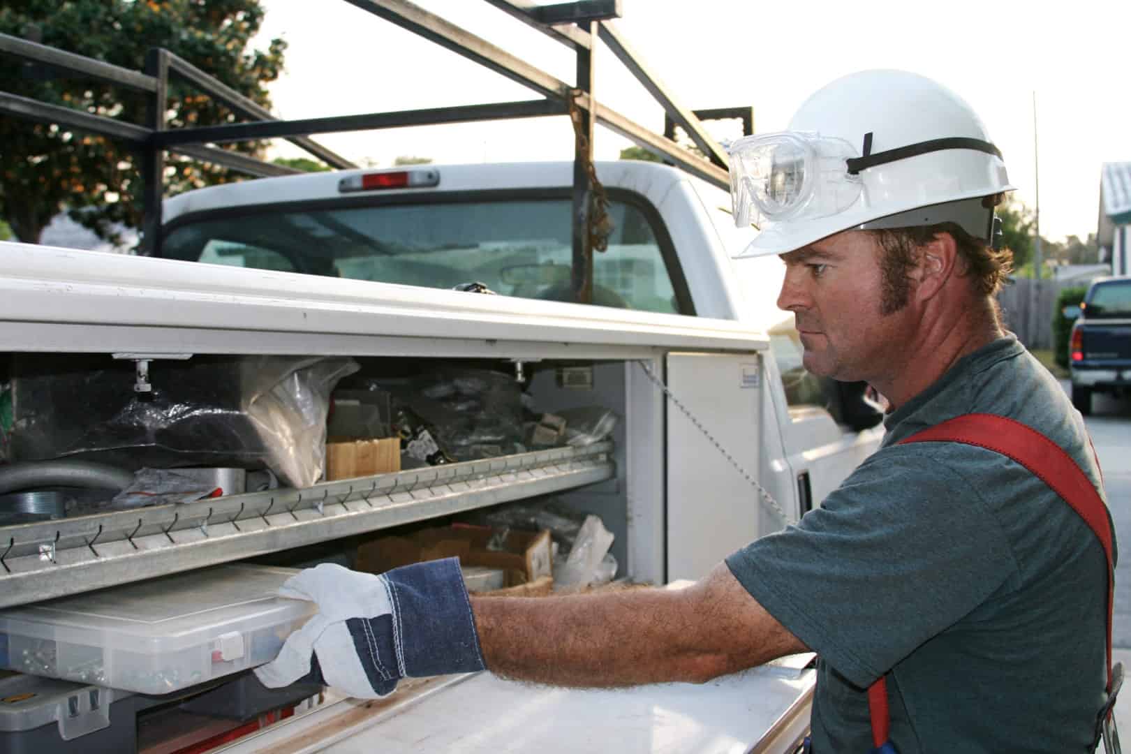Man removing parts box from toolbox mounted on truck.
